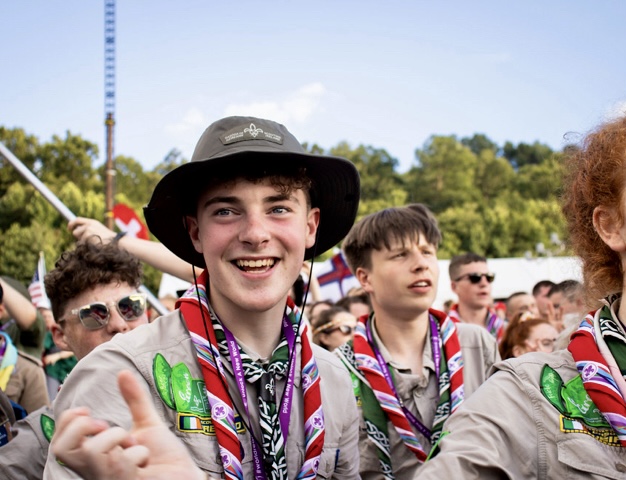 Adam Ó Ceallaigh in his scout uniform surrounded by other scouts at a jamboree