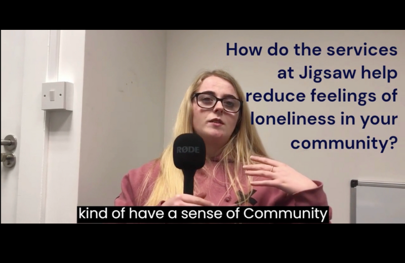 A blonde woman in a pink shirt is asked how the services at Jigsaw help reduce feelings of loneliness in her community