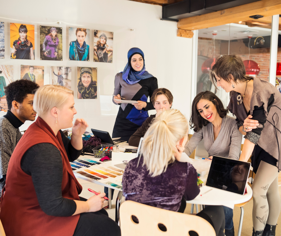 a diverse group of people sit around a table in a work environment