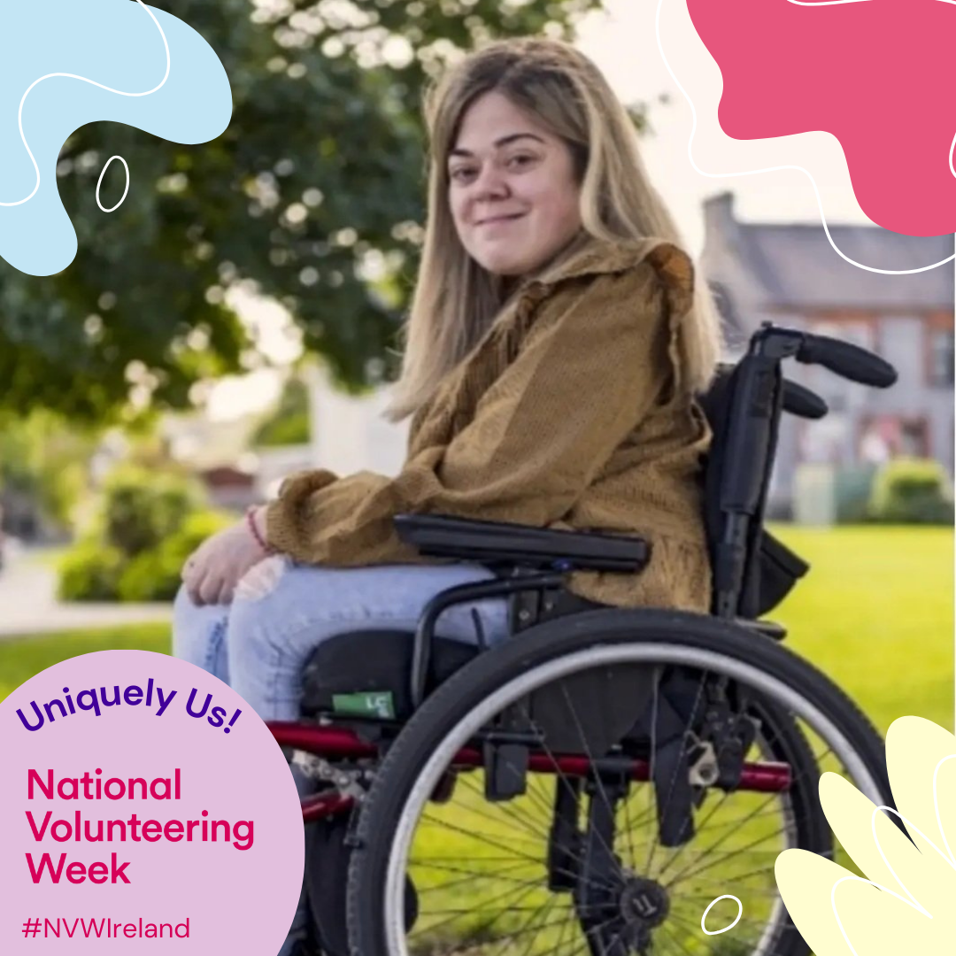 A smiling blong woman using a wheelchair facing sideways outside